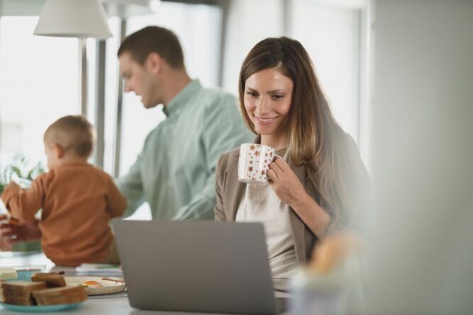 Woman Working from Home Husband in Background